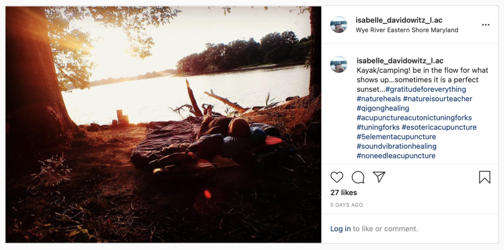 Instagram post of Isabelle Davidowitz laying waterside of her sleeping bag at Wye River Eastern Shore Maryland with the caption, "Kayak/camping! be in the flow of what shows up... sometimes it is a perfect sunset...".